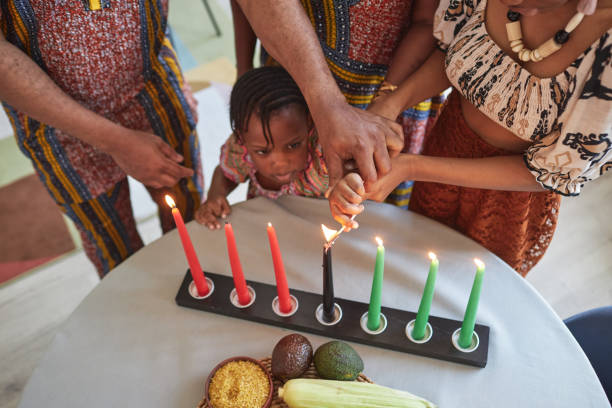 petite fille africaine brûlant des bougies avec sa famille - kwanzaa photos et images de collection