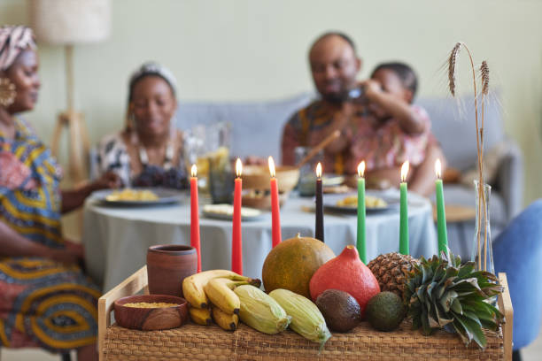 Traditional decoration for Kwanzaa celebration Close-up of traditional decoration with candles and exotic fruits for Kwanzaa celebration with family having dinner in background angolan kwanza photos stock pictures, royalty-free photos & images