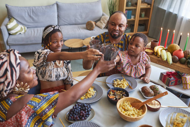 African family celebrating holiday together at home Happy African family of four toasting with drinks during holiday dinner at home angolan kwanza photos stock pictures, royalty-free photos & images