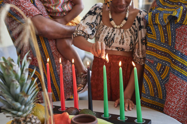 African family of four lighting candles Close-up of African family of four in national costumes burning all seven candles for Kwanzaa holiday angolan kwanza photos stock pictures, royalty-free photos & images