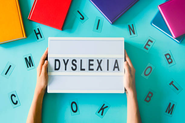 istock Dyslexia awareness, help children with reading, learning difficulties concept. Kid hand holding lightbox with DYSLEXIA word. Colorful books and different letters on light blue background. Top view 1425284205