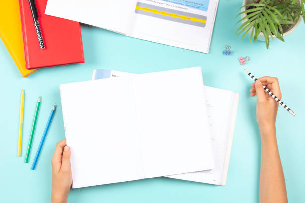 istock Child doing homework. Top view to desk with open blank notebook, books, colored overlay strips for Dyslexia students, school supplies. Education, learning disability, reading difficulties, dyslexia 1425284317