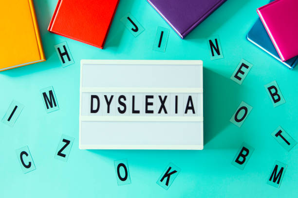 istock Dyslexia awareness, help children with reading, learning difficulties concept. Lightbox with DYSLEXIA word. Colorful books and different letters on light blue background. Top view 1425284483