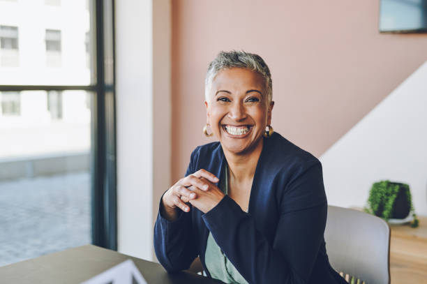Senior, happy and smile of a proud corporate woman ceo of a company at her office desk. Portrait of a business leader, manager and boss feeling worker, career and management success at a company stock photo