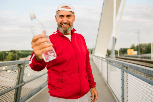 istock Senior man standing alone and drinking water after a workout 1425292998
