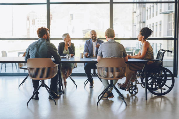 disability, diversity and business meeting with staff, people or team communication, planning on corporate strategy, goal or mission for kpi. woman in wheelchair in group talking of company inclusion - sakinlik stok fotoğraflar ve resimler