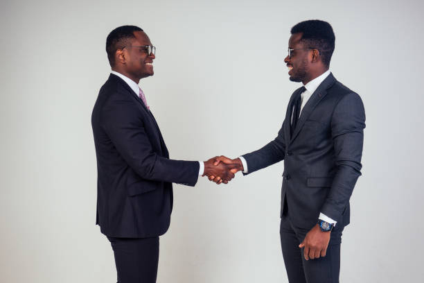 handshake wiht African american bank manager and dark-skinned owner ceo business man in the studio on a white background. multinational teamwork high five handshaking stock photo
