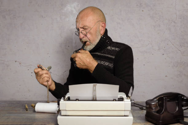 Autor at work looks at the clock. Desk with telephone and typewriter. Vintage. Writer editor.