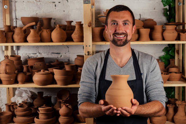 töpfer profi glücklicher mann, der mit braunem ton in der werkstatt arbeitet. geschäftsmann künstler handel handmade pot shop - skulptur kunsthandwerkliches erzeugnis stock-fotos und bilder