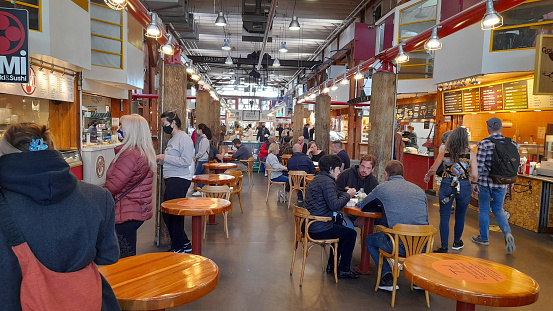 Granville Island Public Market In Vancouver British Columbia Canada, Variety Of Pastry On Display For Sale, People Standing, Eating And Drinking, Buying Food And Drink, Wearing Non Medical Face Mask Due To COVID-19 Pandemic Scenery During Autumn Season