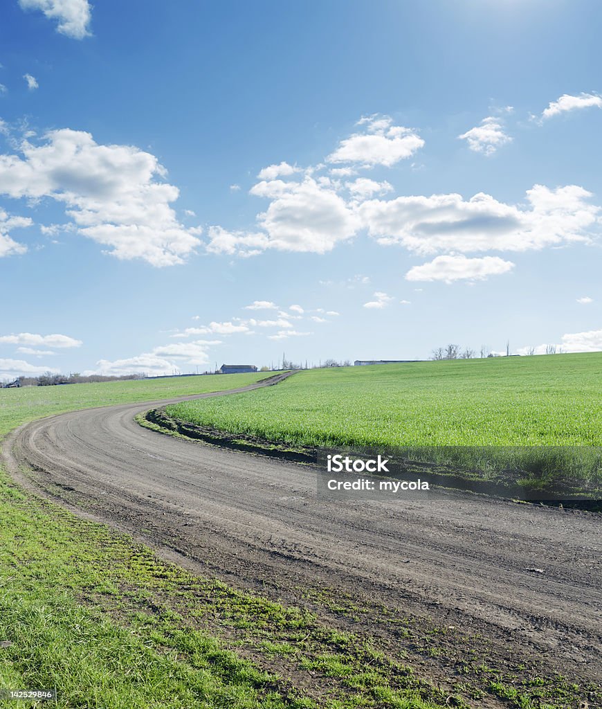 winding rural road under blue cloudy sky Backgrounds Stock Photo