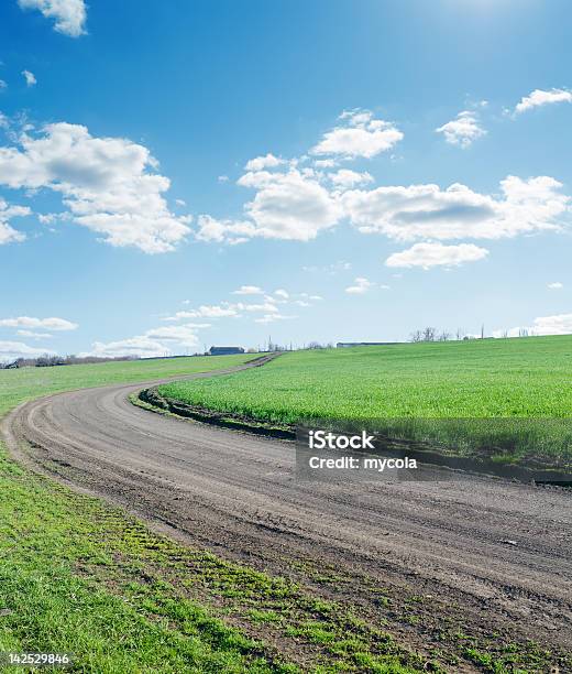 Winding Rural Road Under Blue Cloudy Sky Stock Photo - Download Image Now - Backgrounds, Blue, Direction