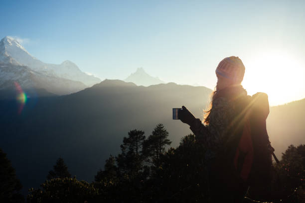A beautiful and active woman holds a cup with a hot drink in her hands. the concept of active recreation and tourism in the mountains. trekking in Nepal Himalayas stock photo