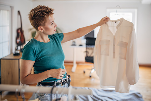 Beautiful shorthaired woman standing at home and choosing what clothes to wear today.