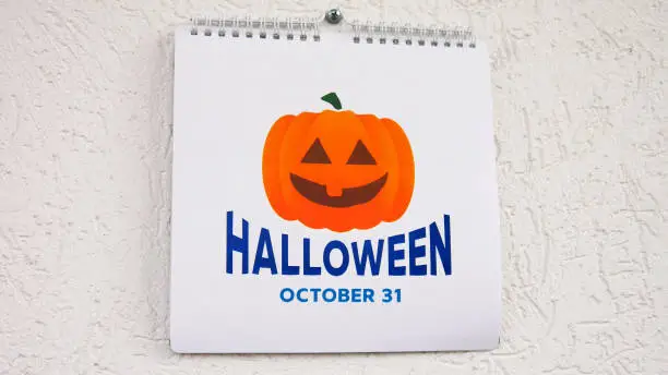 Photo of Close-up of the page of a wall calendar with big orange pumpkin symbol and the date of Halloween