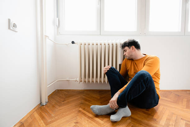 istock A man is sitting in an empty cold room, beside the radiator 1425311324