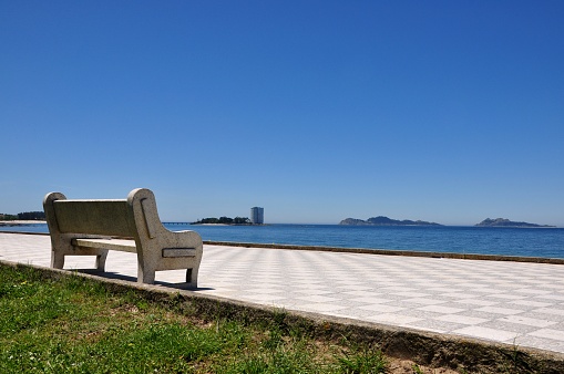 Bench on a public walking close to the coastline  with sea views over Cies Islands. Samil beach in Vigo, Spain