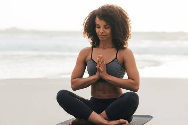 istock Slim female with closed eyes folded hands while sitting in Sukhasana pose at sunset 1425320517