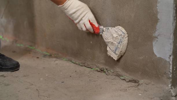 istock The master on a metal spatula applies the solution to the wall for leveling. The master applies the solution with a spatula. 1425329174