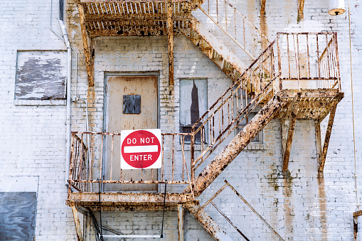 Very rusty exterior stairwell on a building with a do not enter sign