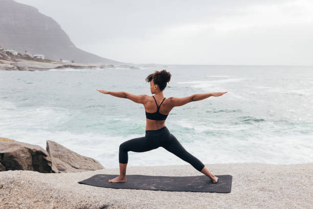 istock Rear view of slim female practicing warrior pose by ocean 1425334644