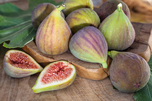 Raw sweet figs on a wooden background closeup. Red - purple e green figs. Figs whole and cut into halves. Organic gardening. High quality photo