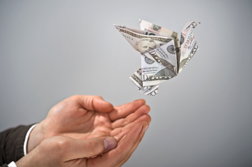 A man holding hands out with money bird flying away