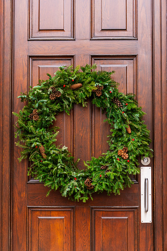 Christmas traditional wreath hanging on wooden front door
