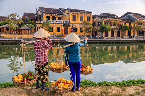 Mujeres vietnamitas que venden frutas tropicales, casco antiguo en la ciudad de Hoi An, Vietnam photo
