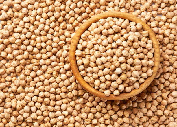 istock wooden plate with chickpeas on a raw chickpeas background close-up top view. 1425346829