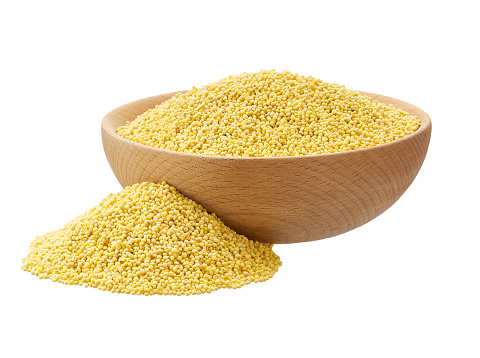 Raw millet yellow grains in a wooden bowl isolated on white background.