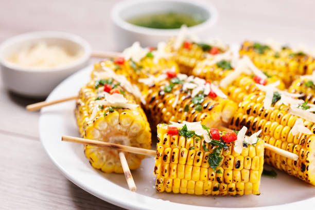 istock Chili and cheese grilled corn on cob, selective focus. Plate with grilled corn on cob sprinkled with cilantro and grated parmesan  on light background. 1425357155