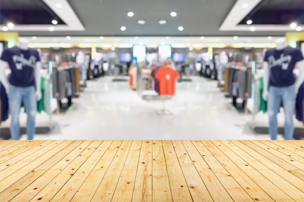 Empty wood table top with blur clothing boutique display interior shopping mall background