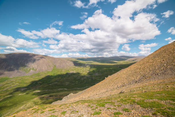 paysage de montagne pittoresque avec vallée verdoyante avec rivière et chaîne de montagnes avec la lumière du soleil et les ombres des nuages par temps changeant. paysage alpin coloré avec des montagnes ensoleillées et un ciel nuageux. - russia river landscape mountain range photos et images de collection