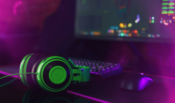 istock Computer gaming mouse and keyboard with purple backlight next to green headphones opposite the monitor 1425367159