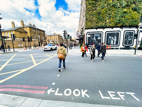 London, United Kingdom - March 6 2022: from both directions people are crossing a street on a pedestrian crossing