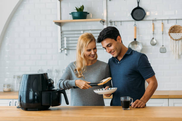 Couple preparing meal in air fryer stock photo