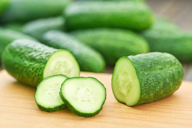 istock Whole and sliced cucumbers on a cutting board, close up. 1425377713