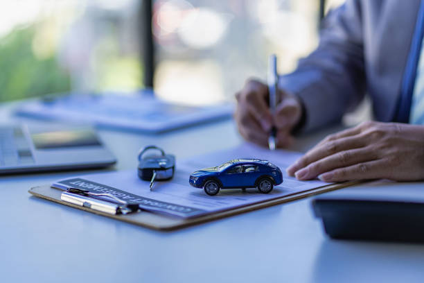 concepto de venta de automóviles, los representantes de ventas dan las llaves a los clientes en la mesa con pequeñas muestras de automóviles y seguros de oficina. - car insurance sales occupation buying fotografías e imágenes de stock