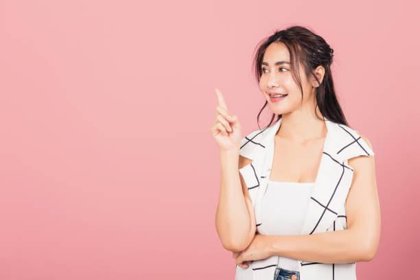 istock woman standing smiling indicate finger empty space 1425388566