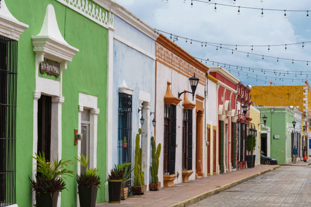 de vieux bâtiments colorés et des plantes en pot bordent une rue étroite de campeche - campeche photos et images de collection