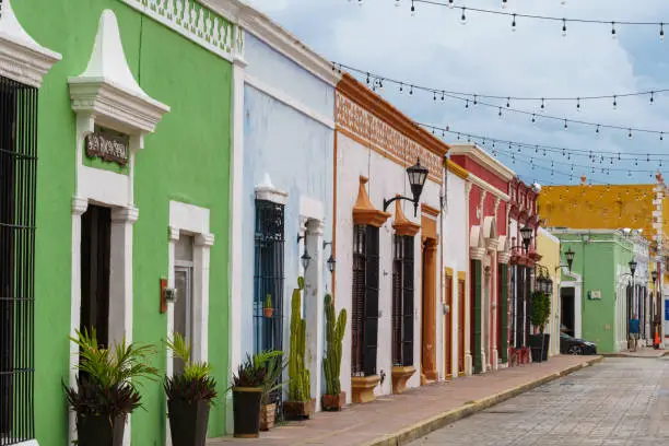 Colorful old buildings and potted plants line a narrow street in Campeche, Mexico