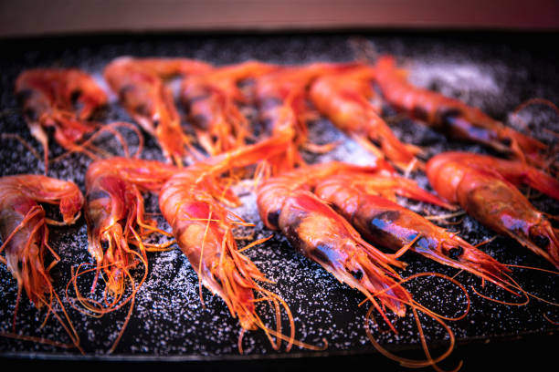 cooking tiger shrimps on iron griddle. selective focus. close up cooking tiger shrimps on iron griddle. selective focus. close up food state preparation shrimp prepared shrimp stock pictures, royalty-free photos & images