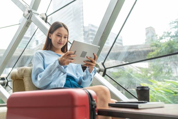 istock Beautiful young asian female solo lady traveller watching content on her digital tablet while waiting for departure in a cafe in airport terminal 1425404328
