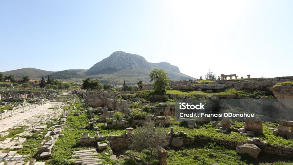 Acro Corinth in distance, with ancient ruins in foreground Ancient Greece boast spectacular ruins and this open land reveals the might Acro Corinth tower with the ruins of first century Corinth beneath. Apostle - Worshipper Stock Photo