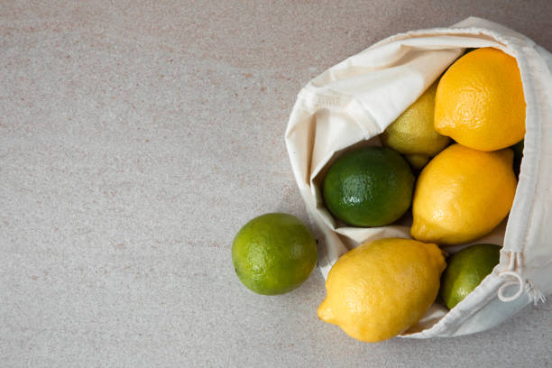 istock Fresh lemons and limes in a fabric bag on a light stone background 1425410796