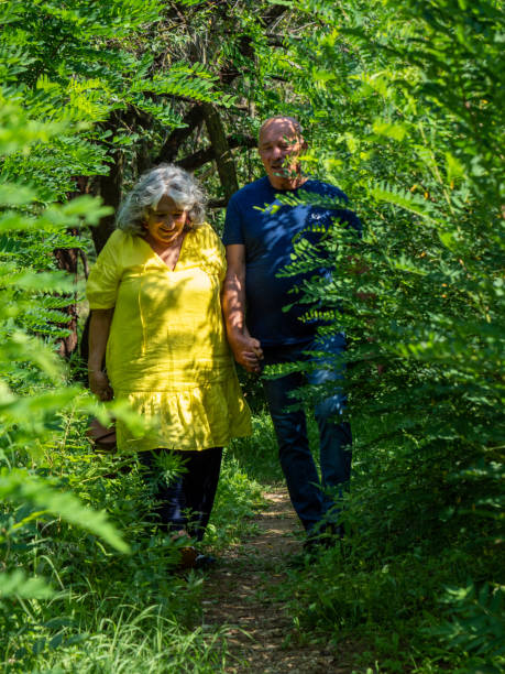 夏の公園で先輩男女が手をつないで - 永遠の愛のコンセプト - holding hands couple senior couple togetherness ストックフォトと画像