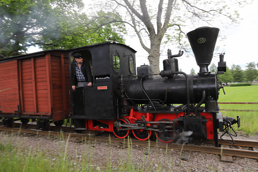 Mariefred, Sweden - June 4. 2022: Steam locomotive number 10 Avesta with traiver pulling a narrow gauge museum train.