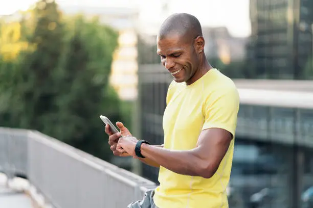 Photo of Man synchronizing cellphone and smartwatch to do sports in the city