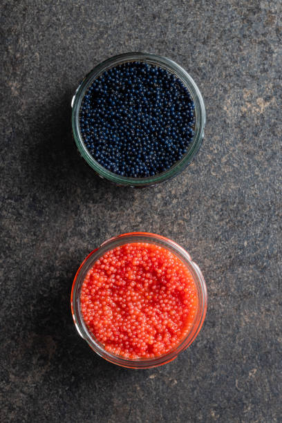 暗いテーブルの上の瓶に入った赤と黒のキャビア。 - caviar salmon red gourmet ストックフォトと画像